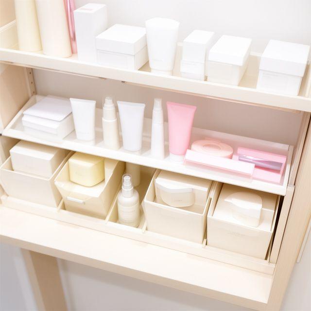 Sauber beschriftete Pflegeprodukte und Aufbewahrungsboxen in einem hellen Beauty-Regal
